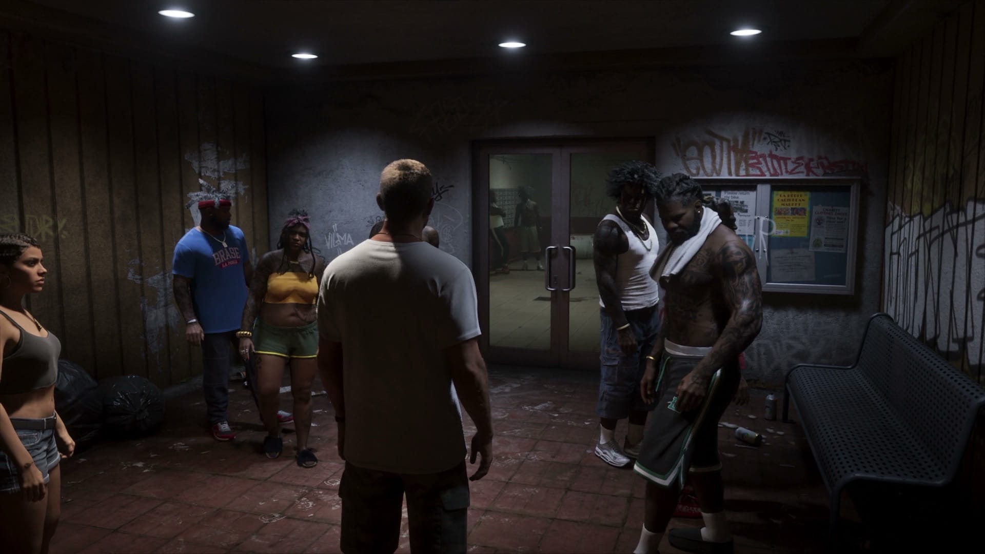 A group of people standing around a graffitied, litter-strewn lobby interior in Grand Theft Auto VI