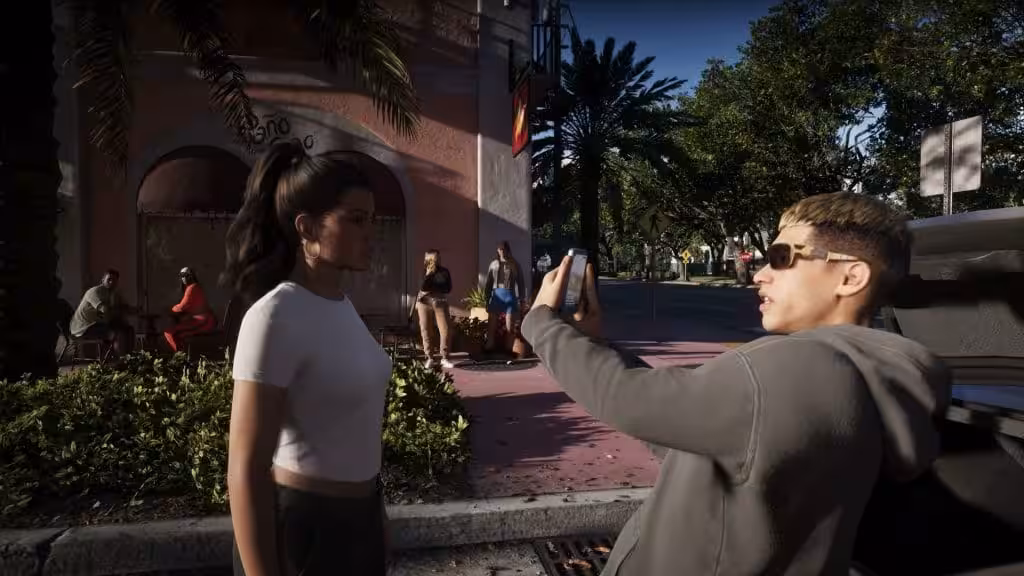 A man filming a woman on his phone on a Vice City sidewalk in Grand Theft Auto VI