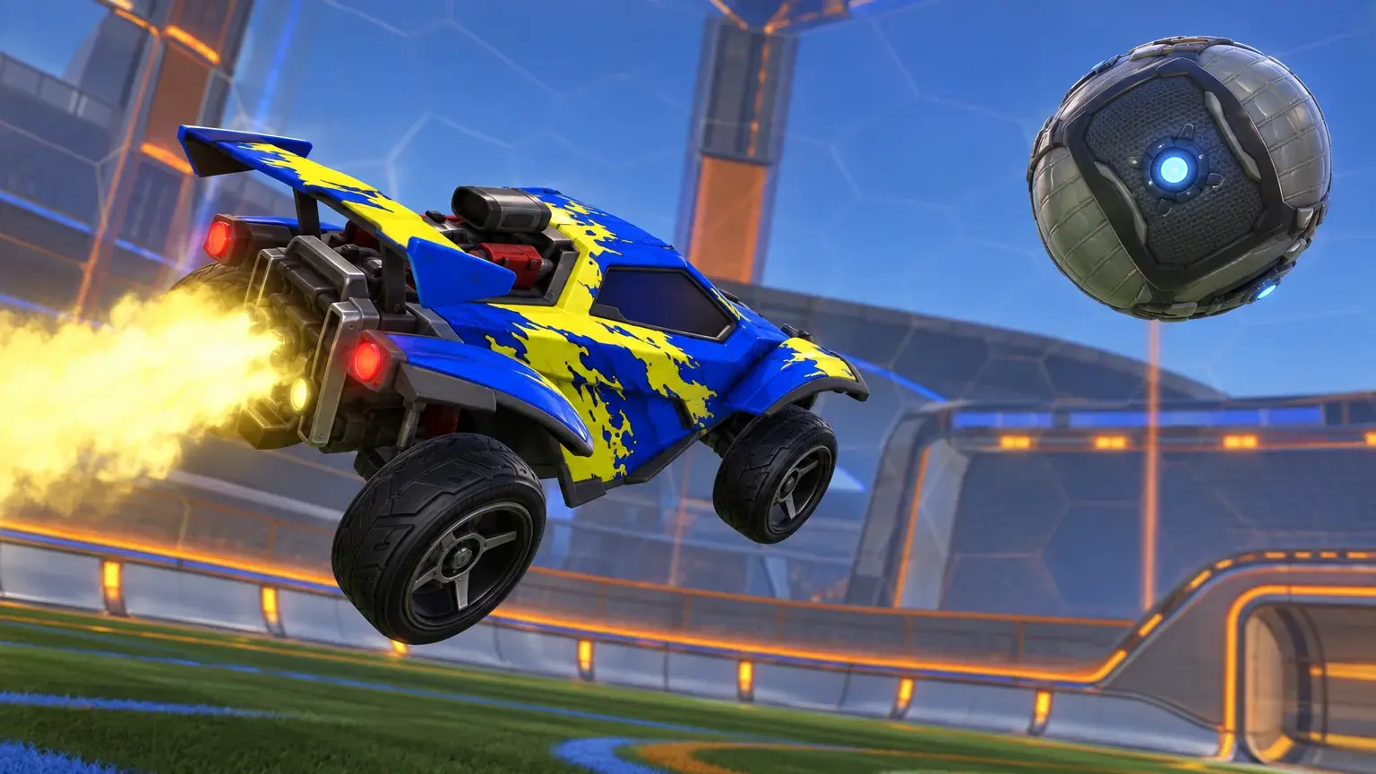 Blue-yellow car with flame boost leaps toward metallic ball in open Rocket League stadium.