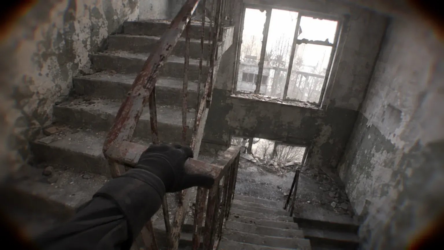 A gloved hand rests alone on a railing in an empty stairwell under flat grey light.