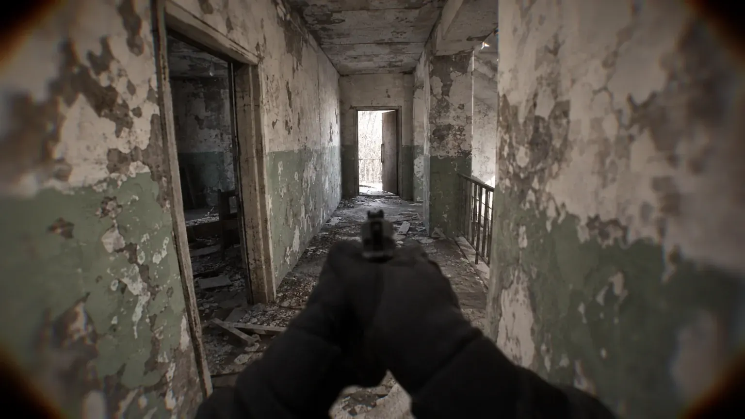 A narrow derelict corridor with peeling walls and a doorway at the far end.